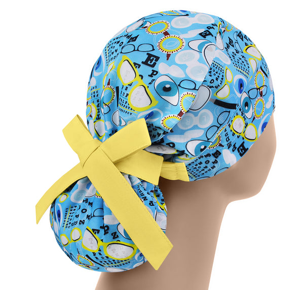 Blue scrub cap with eyeglasses pattern and yellow bow on a mannequin head against a white background